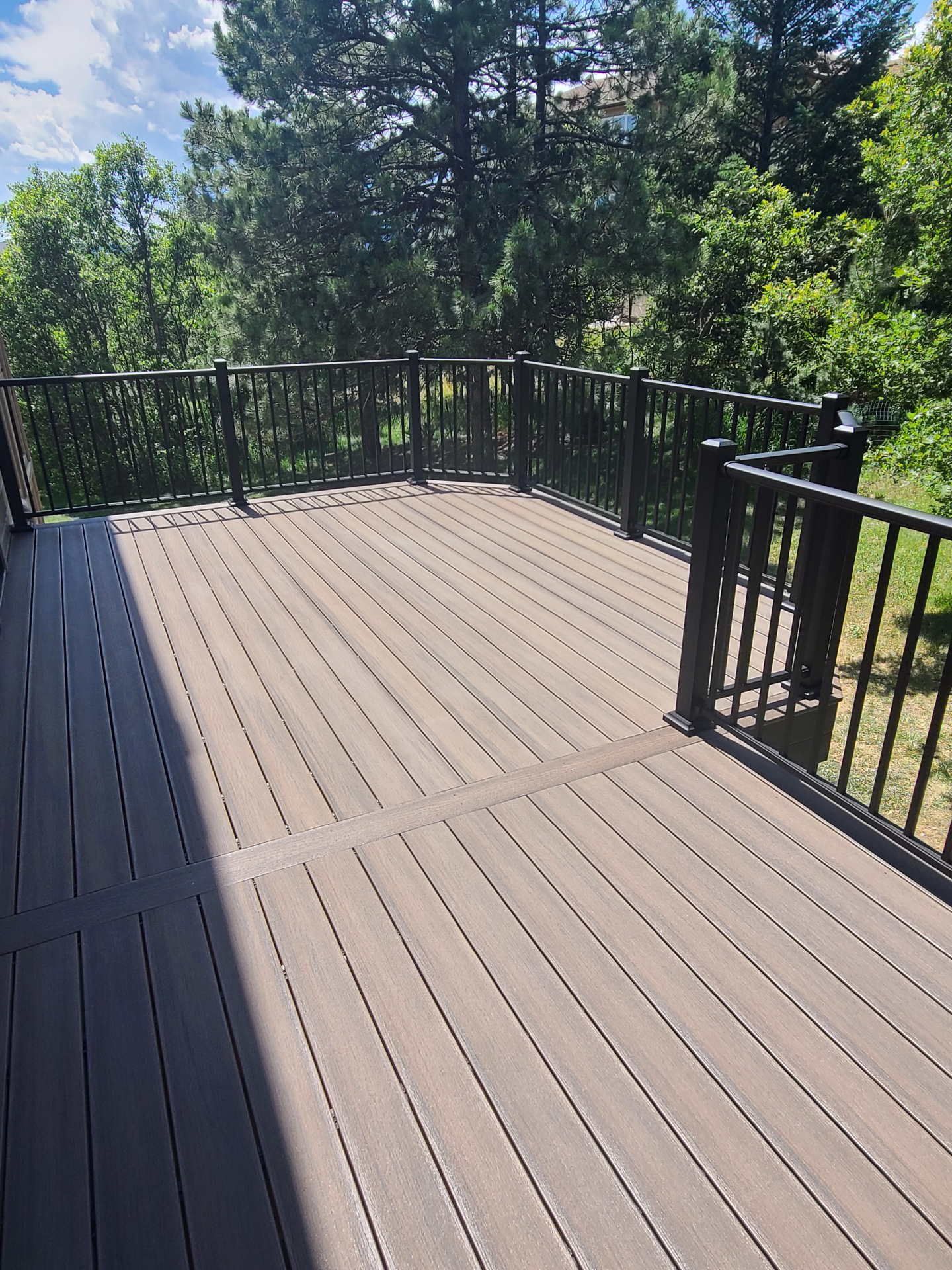 Composite deck with black metal railings overlooking Colorado pines